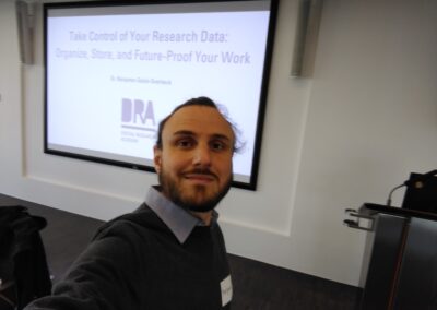 Picture of me in front of the first slide of the workshop. The title of the slide is "Take Control of your research data: Organize, Store and Future-Proof your work"
